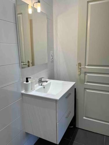 La salle de bains est pourvue d'un lavabo, d'un miroir et d'une porte. dans l'établissement Le coco(n) Paimpolais classé 2 étoiles, à Paimpol