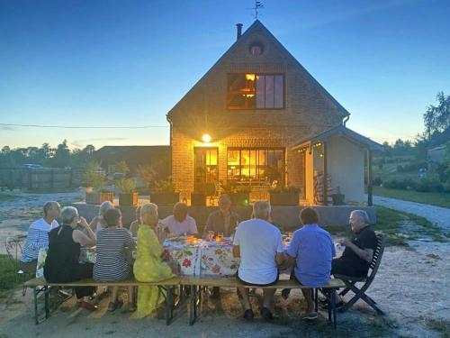 a group of people sitting around a table in front of a house at LA LONGERE GALOPE in Sainte-Gauburge-Sainte-Colombe