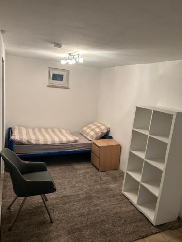um pequeno quarto com uma cama e uma cadeira em Gästehaus - Klingengasse 2, Rainau em Rainau