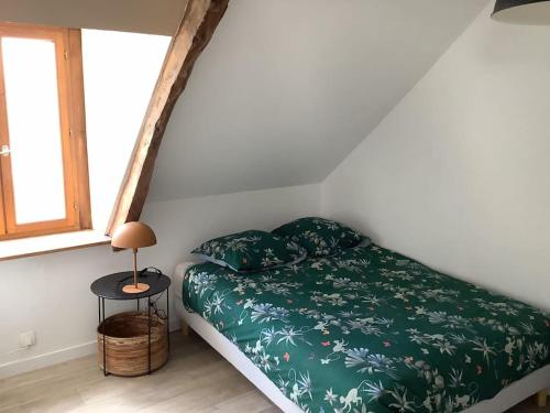 - une chambre avec un lit doté de draps verts et une fenêtre dans l'établissement La maison d’Eugenia, à Paimpol