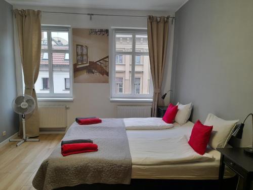 ヴロツワフにあるNovitas Apartmentsのベッドルーム1室(赤い枕のベッド2台付)