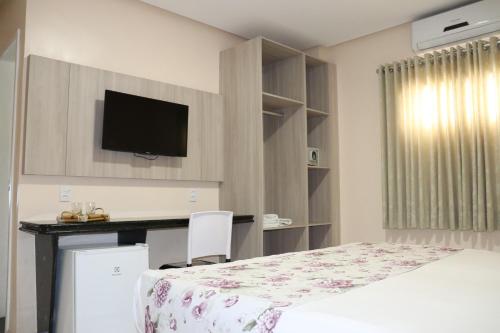 Schlafzimmer mit einem Bett, einem Schreibtisch und einem TV in der Unterkunft MONTERREY HOTEL in Santa Inês