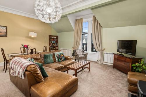 a living room with a couch and a tv at Panoramic Sea Views - Stunning 3BD Apt & Balcony in Oban