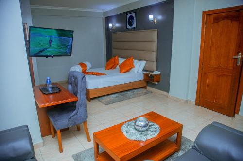 a bedroom with a bed and a table and a television at LE GRAND MARIE HOTEL in Dar es Salaam