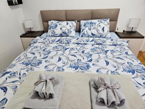 a bed with blue and white sheets with towels on it at Apartman Vukota Pirot in Pirot