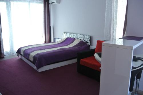 a bedroom with a bed and a red chair at Apartment Izabela in Primorsko