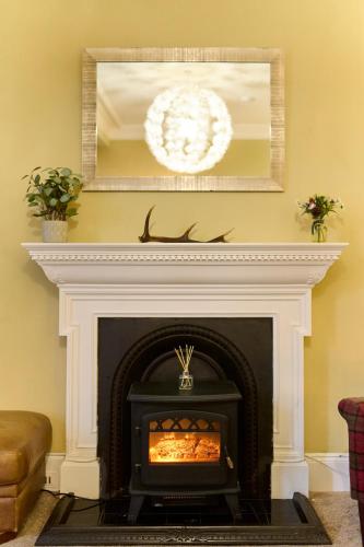 a fireplace in a living room with a mirror at Panoramic Sea Views - Stunning 3BD Apt & Balcony in Oban