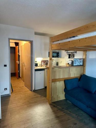 un salon avec un canapé bleu et une cuisine dans l'établissement RDC La joue du loup, à Saint-Étienne-en-Dévoluy