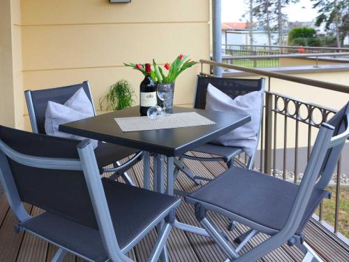 a black table and chairs on a balcony with flowers at Exkl App Silbermöwe, 100 m zum Strand mit WLAN in Börgerende-Rethwisch