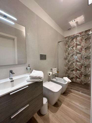 a bathroom with a sink and a toilet and a mirror at Othalan Home in Paestum