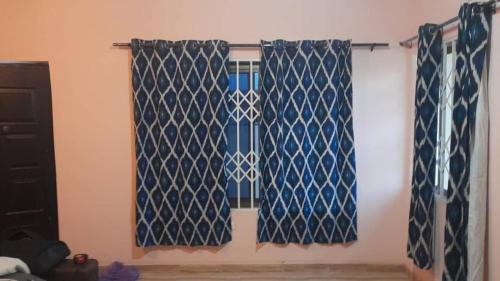 2 blaue und weiße Vorhänge in einem Zimmer in der Unterkunft Frafraha Cottage in Accra