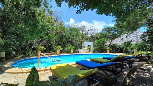 basen z szezlongami i krzesłami obok niego w obiekcie Bamba Kofi Tented Camp w mieście Watamu