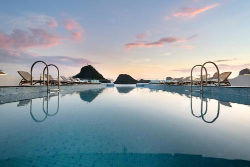 a infinity pool with chairs and mountains in the background at Grand Pioneers Halong Bay Cruise 1 in Ha Long