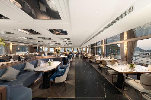a restaurant with tables and chairs and windows at Grand Pioneers Halong Bay Cruise 1 in Ha Long