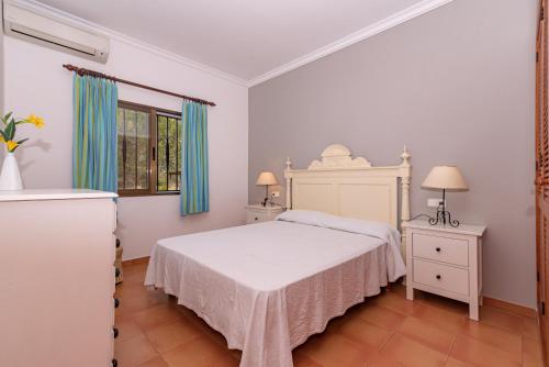 a bedroom with a white bed and blue curtains at Villa Vilar by Sealand Villas in El Port