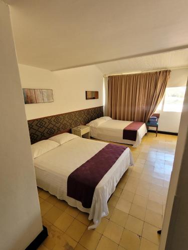 a hotel room with two beds and a window at Hotel Gimaura in Ríohacha