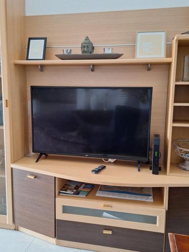 a flat screen tv in a wooden entertainment center at Piso California 3 aire acondicionado, wifi, cerca del mar in Miami Platja