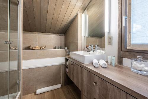 une salle de bain avec un lavabo, une baignoire et une douche dans l'établissement Chalet Satine - Luxe au pied des pistes, à Demi-Quartier