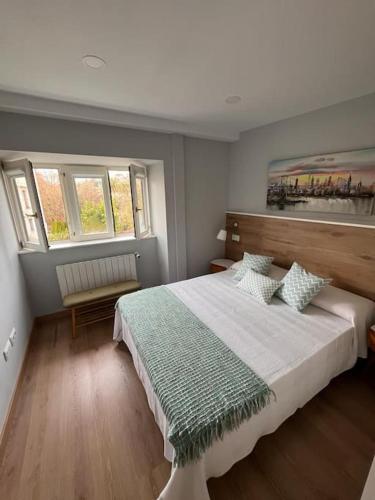 a bedroom with a large bed and two windows at Apartamento Bolingas in Comillas