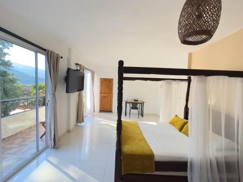 a bedroom with a bed and a balcony with a tv at Curazao Hotel -Centro Histórico- in Santa Fe de Antioquia