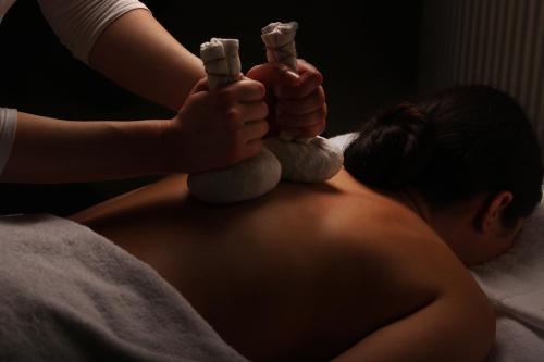 a woman laying on a bed holding two miniature figures at Cit'Hotel Le Relais du Boisniard in Chambretaud