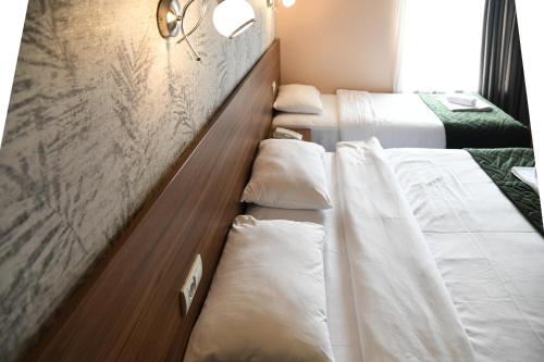 szereg łóżek w pokoju hotelowym w obiekcie Hotel Garden w Nowym Sadzie