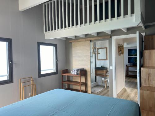 ein Schlafzimmer mit einem blauen Bett und einem Loft in der Unterkunft Le Belvédère in Saint-Leu