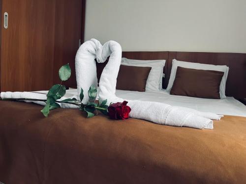 a bed with two towels and two roses on it at Slavyanska Beseda Hotel in Sofia