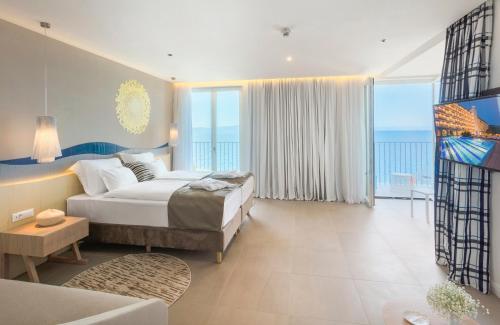 a bedroom with a bed and a large window at Bluesun Hotel Jadran in Tučepi