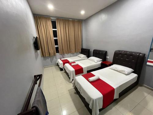 Una fila de cuatro camas en una habitación en SZA INN HOTEL, en Kampong Kerayong