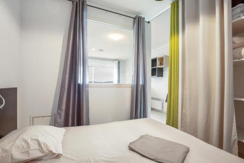 1 dormitorio con cama blanca y ventana en Jakine - Joli T2 avec terrasse, en Azille
