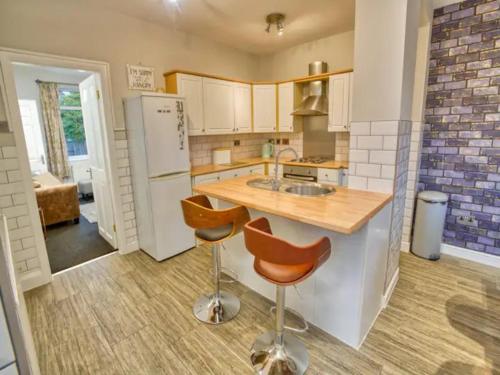 a kitchen with a counter and two stools in it at Pass the Keys Large Family House near Lincoln in North Hykeham