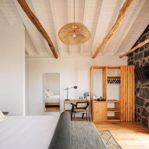a bedroom with a bed and a desk and a table at Adega do Fogo in São Roque do Pico