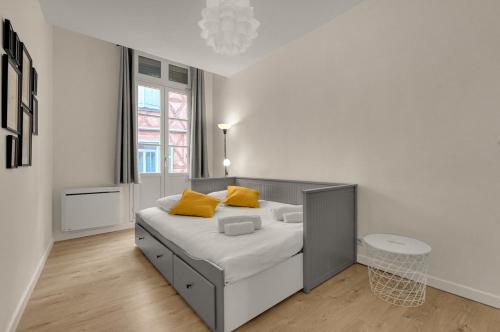 - une chambre blanche avec un lit et des oreillers jaunes dans l'établissement Roma Maximus - coeur historique vieille ville, à Toulouse