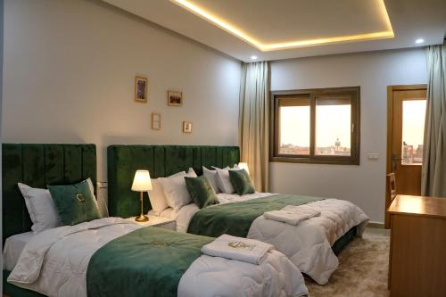 a hotel room with two beds with green covers at Hotel Golden Sunset Dakhla in Dakhla