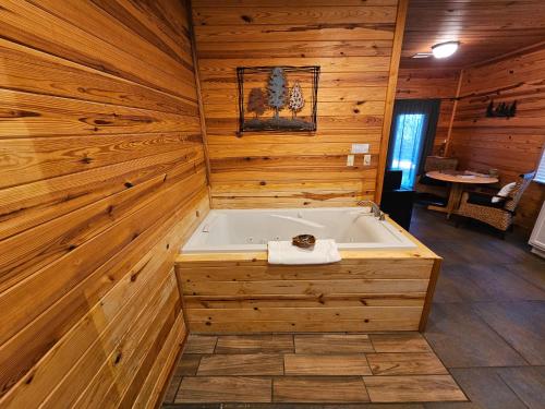Cette chambre dispose d'une baignoire et d'un mur en bois. dans l'établissement Honey Bear Haven Suite 1, à Eureka Springs