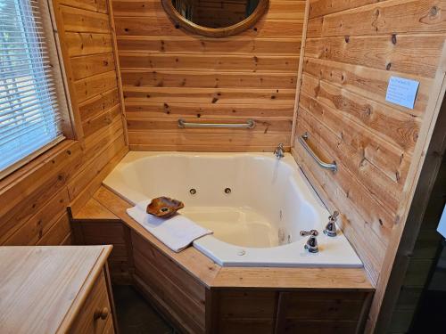 a tub in a wooden bathroom with a sink at 5 Min To Beaver Lake King Bed Fire Pit Jetted Tub #4 in Eureka Springs