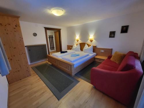 a bedroom with a bed and a red couch at Schütterhof in Ramsau am Dachstein