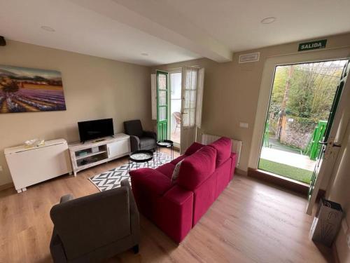 uma sala de estar com um sofá vermelho e uma televisão em Casa Bolingas - Apto 5 em Comillas