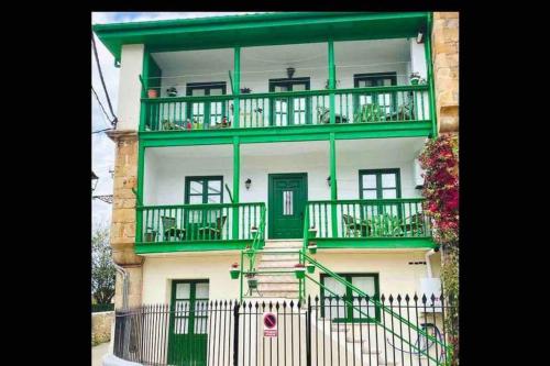 um grande edifício com acabamento verde e uma varanda em Casa Bolingas - Apto 5 em Comillas