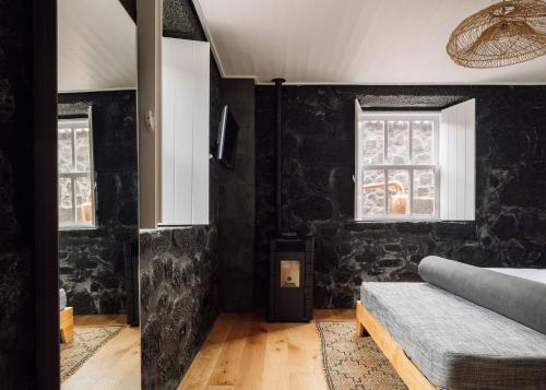 a bedroom with black stone walls and a bed at Adega do Fogo in São Roque do Pico