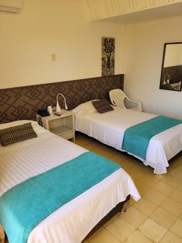 a hotel room with two beds and a table at Hotel Gimaura in Ríohacha