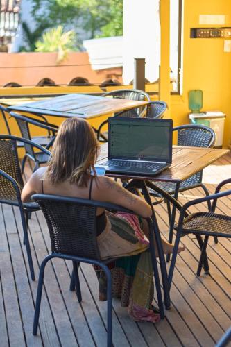 a woman sitting at a table with a laptop at Curazao Hotel -Centro Histórico- in Santa Fe de Antioquia