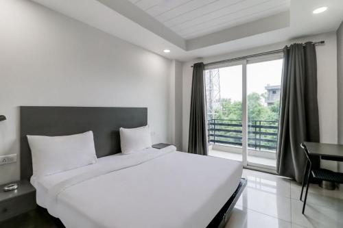 um quarto com uma grande cama branca e uma janela em RJK Stay - Sohna Road em Gurgaon