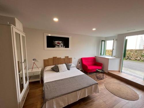 1 dormitorio con 1 cama y 1 silla roja en Estudio Bolingas, en Comillas