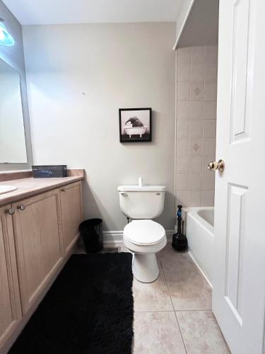 a bathroom with a white toilet and a bath tub at A Room in Oshawa, Free Parking in Oshawa