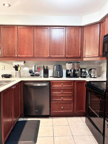 a kitchen with wooden cabinets and a black dishwasher at A Room in Oshawa, Free Parking in Oshawa