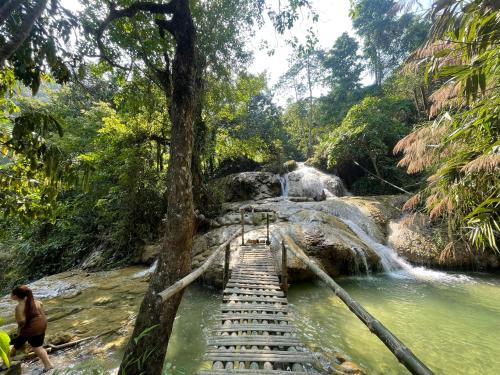 a woman walking over a bridge over a waterfall at Pu Luong - Duy Phuong Homestay in Thanh Hóa