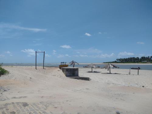 uma praia arenosa com um banco e guarda-sóis em Casa Village Praia em Almfala
