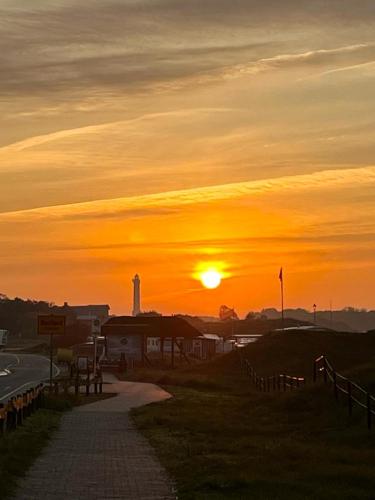 a sunset over a road with a lighthouse in the distance at Haus Naase App 2 in Norderney
